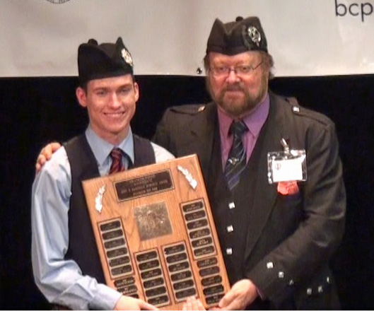 Liam Hilder, winner of the overall title for Amateur Grade 1 Solo Piping, with the trophy from judge Donald Lindsay.
