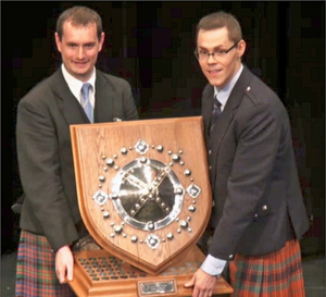 Zephan Knichel (right) presented with the overall Professional Solo Piping trophy from adjudicator Andrew Carlisle at the 2016 Annual Gathering.