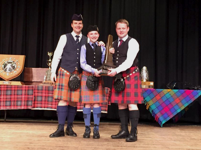 Judge Callum Beaumont (right) presents Alan Bevan (left) and Alistair Bevan with the trophy for most aggregate points gained by any competitor at the 2018 BCPA Annual Gathering, for which the father-son duo tied.