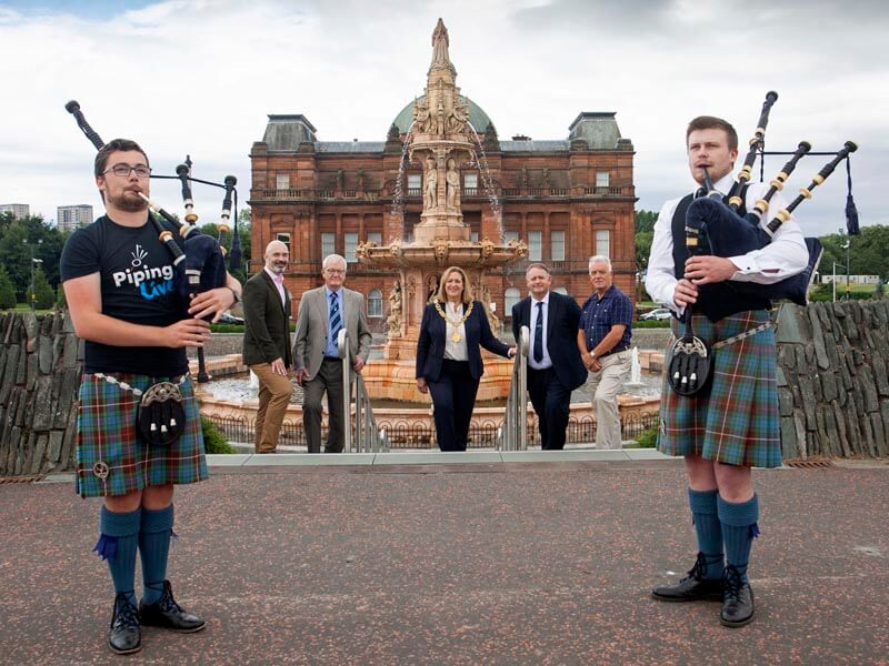 Young pipers from the Grade 1 Peoples Ford Boghall & Bathgate Caledonia playing at Glasgow Green as RSPBA Chief Executive Ian Embelton, Glasgow's Lord Provost Eva Bolander, Piping Live! Director Roddy MacLeod and others look on.
