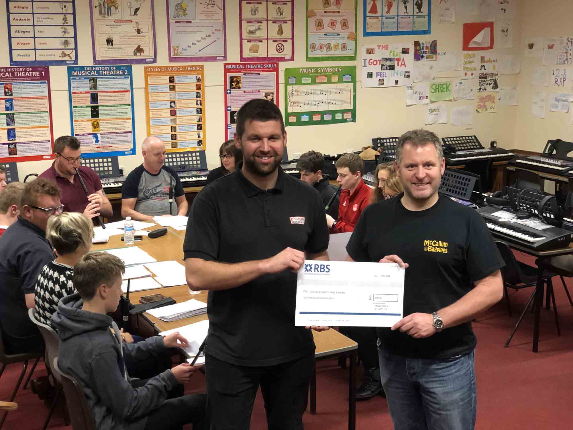 Highland Granite Pipe-Major Scott Oliphant (right) receives a cheque for £6,000 from Fraser Fire & Security.