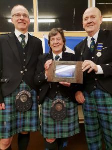 Grade 2 MacKenzie Caledonian former Pipe-Major Neil Nicholson (left) and band President Jim Mills present Anne Spalding with a framed photo of the band.