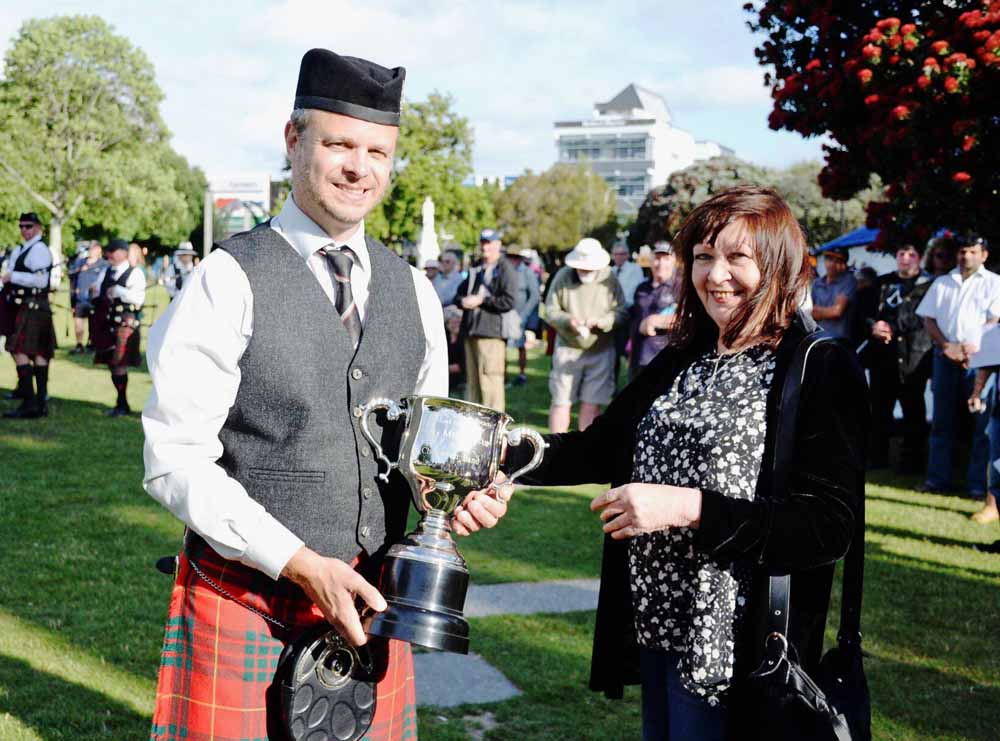 Manawatu Scottish Pipe-Major Stewart McKenzie receives the overall Grade 1 trophy.