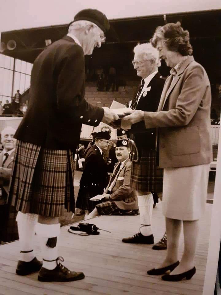 Ballynahinch Pipe-Major Joe McAdam accepts the first prize in Grade 2 at the Cowal Pipe Band Championships.