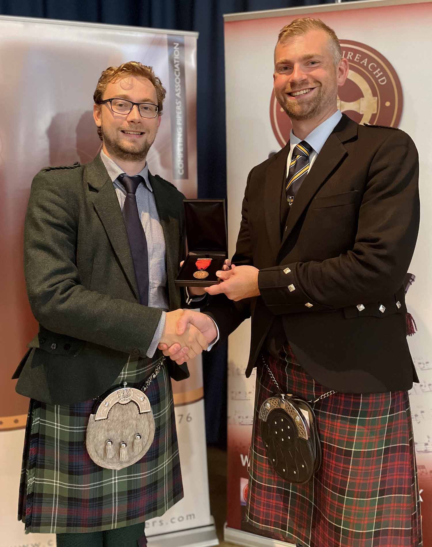 CPA President Derek Midgley (right) presents the first-ever CPA-sponsored Bronze Medal for piobaireachd to Steven Gray.