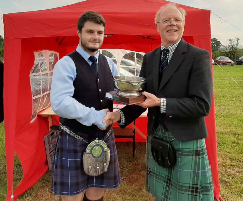 Murray Henderson (right) presents the Jimmie MacGregor Memorial Trophy for the overall C-Grade solo [piping to Bobby Allen.
