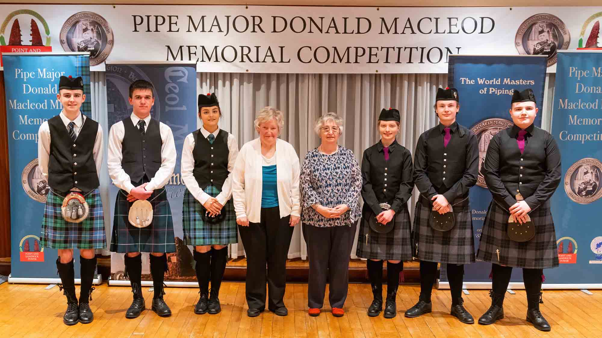 Junior piper with the daughters of P-M Donald MacLeod (L-R): Eosaph Gailbraith, Padruig MacMillan, Fiona MacLeod, Susan Millar, Eilidh MacDonald, Ruairidh MacDonald, and Innes Begg.