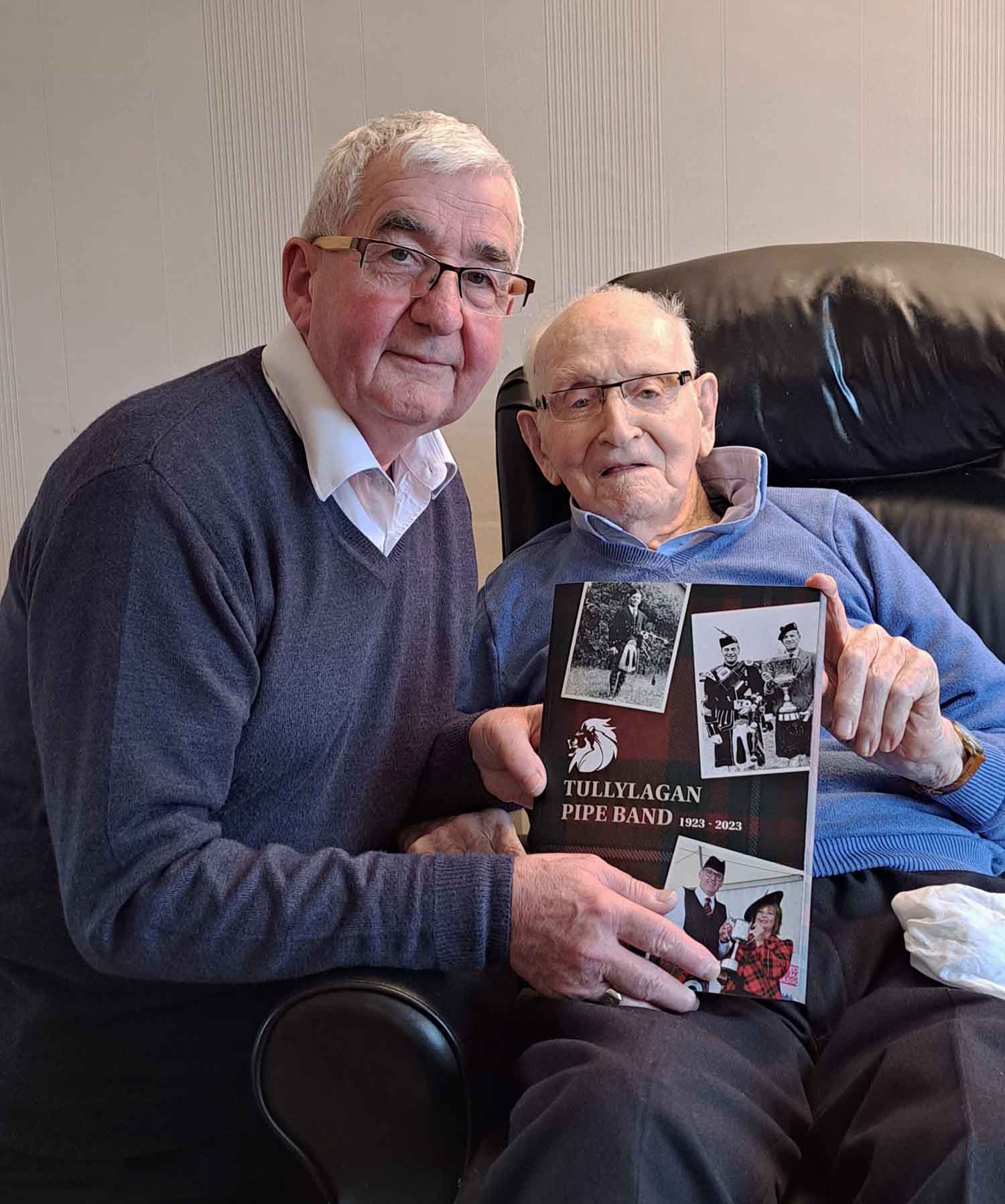 Author Trevor Hassin presents Jim Warnock with a copy of his 'Tullylagan Pipe Band, 1923-2023.'