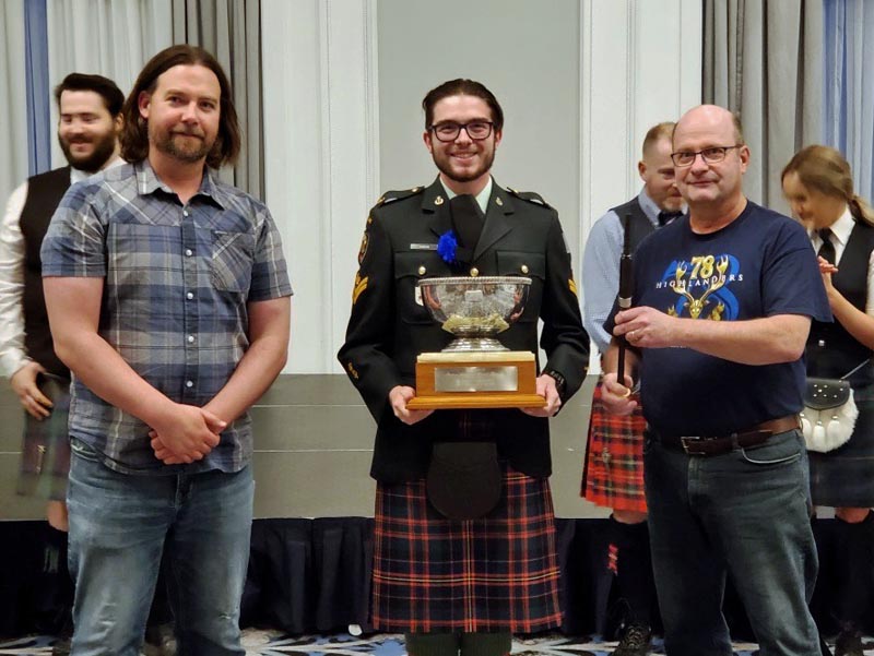 Cameron Dawson (centre) receives the 2023 Saskatchewan Highland Gathering & Celtic Festival amateur piping trophy from organizer Alex Rasmussen (left) and sponsor Iain MacDonald.