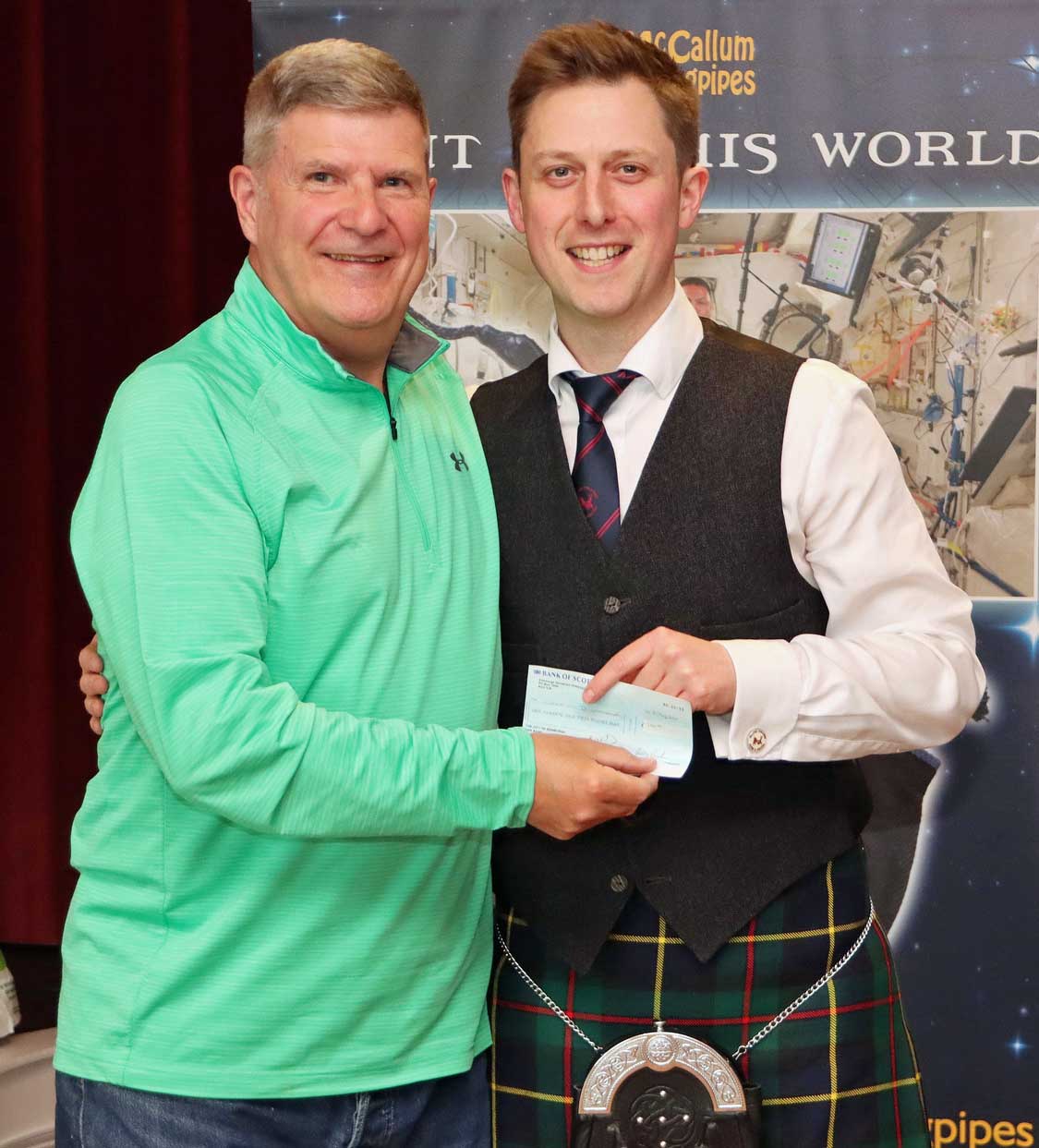 Cameron Drummond (right) receives his cash prize from the Eagle Pipers Society's Euan Anderson for winning the MSR at the annual P-M's Wheel of Fortune competition.
