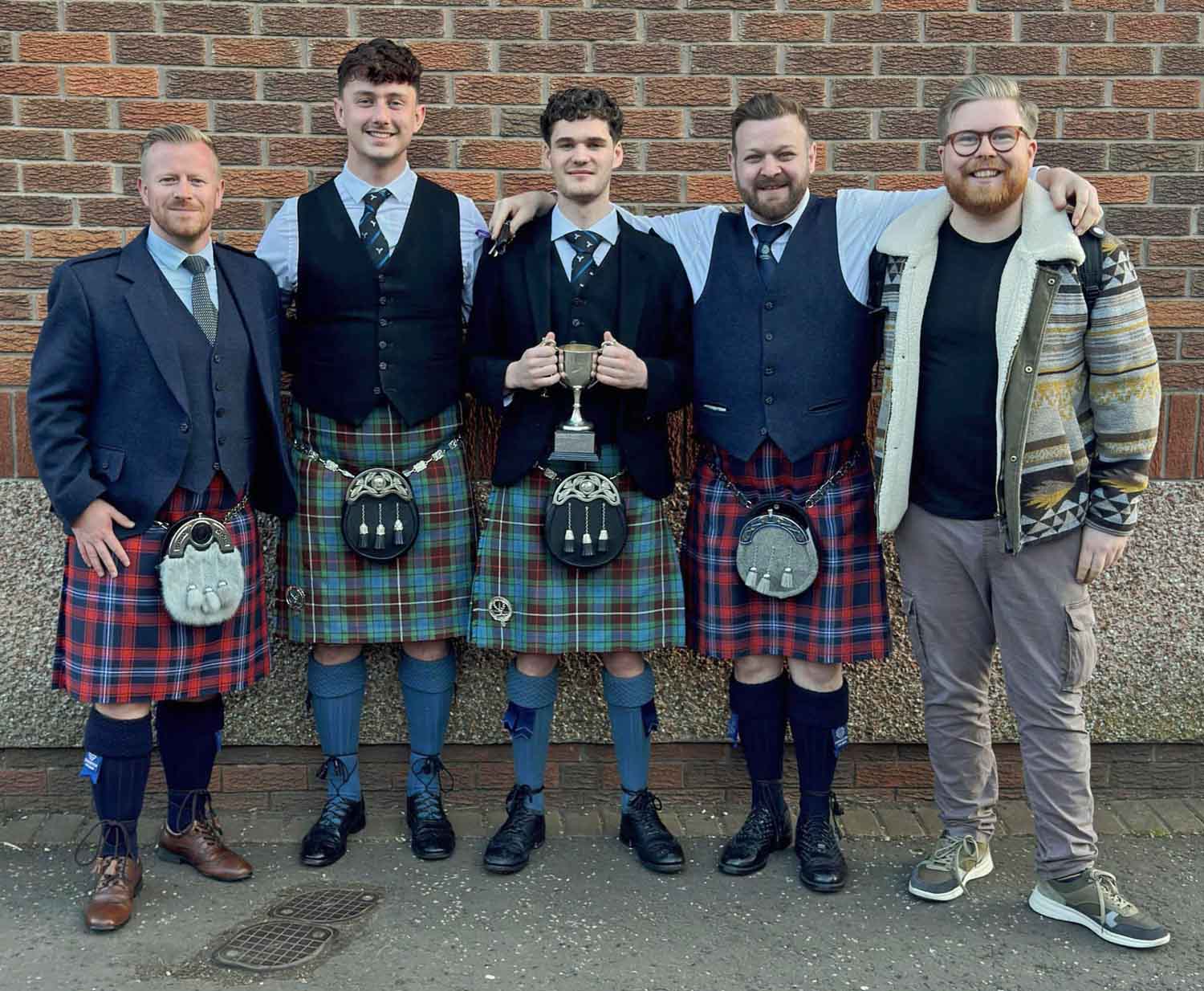 Competitors and their pipers at the 2025 European Solo Drumming Championship (L-R): Craig Munro (piped for Kerr McQuillan); Ewan McDonald; Kerr McQuillan; Craig Lawrie; Danny Hutcheson (played for Lawrie). All are members of the Drums n Roses collective.