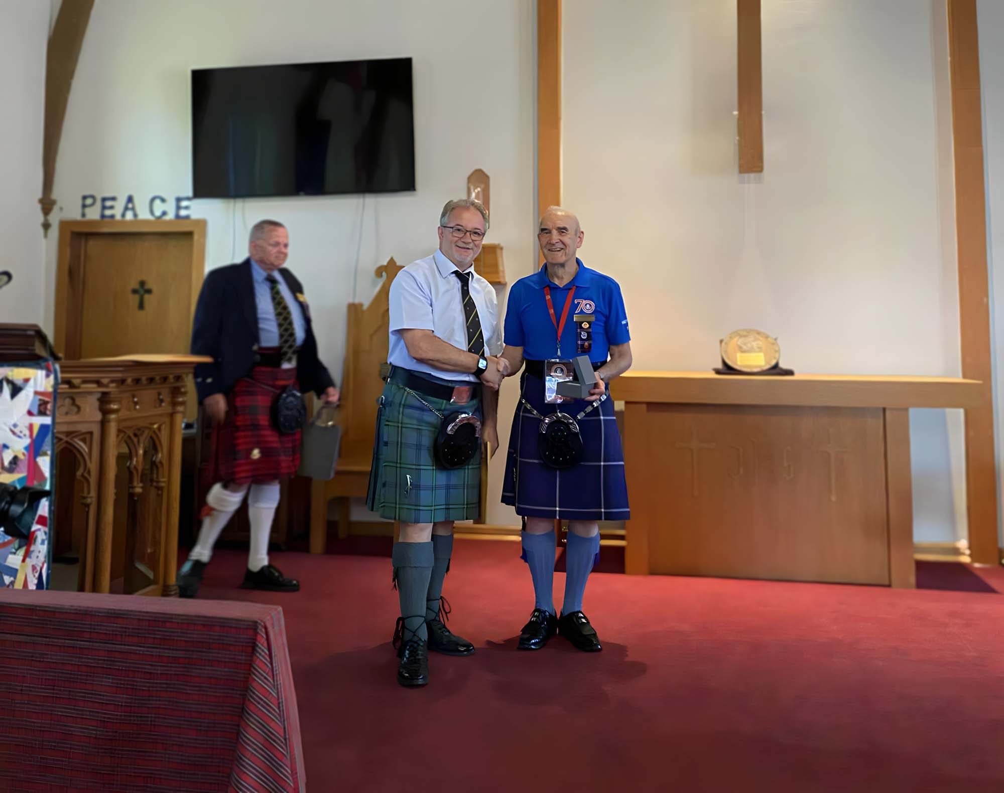 Bruce Gandy receives his fifth Bar to the Piobaireachd Society Gold Medal (Canada) from organizer Jack Yourt.