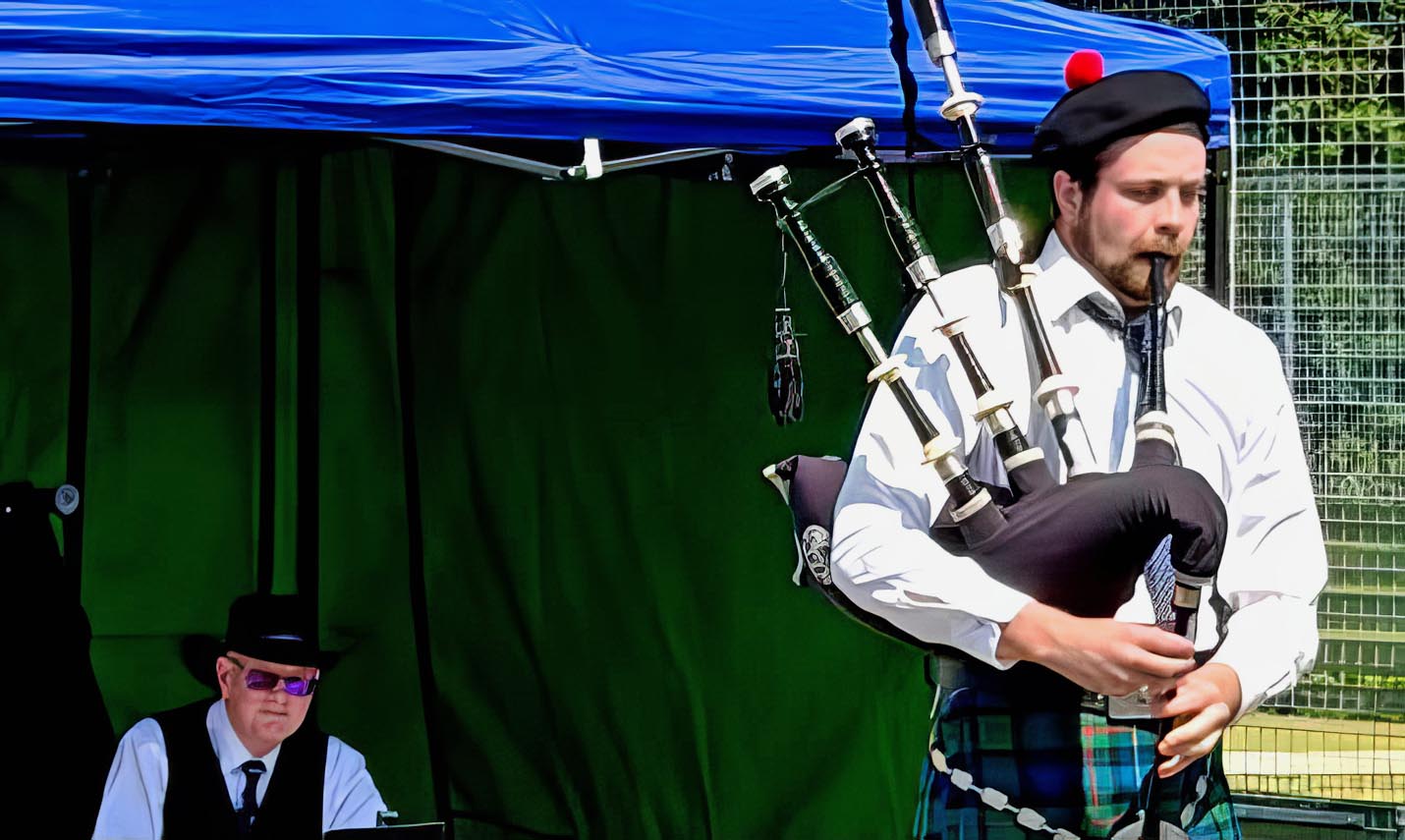 Callum Carn competing in the Senior Piobaireachd at the 2026 Taynuilt Highland Games, while judge Logan Tannock listens.