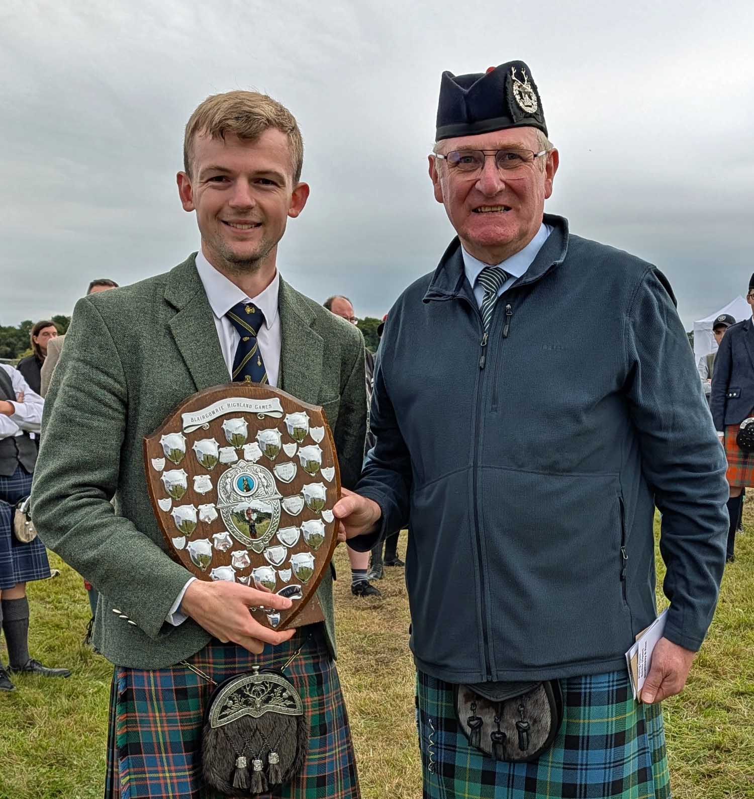 Sandy Cameron (left) receives the Senior overall trophy from organizer Stuart Sampson at the 2026 Blairgowrie & Rattray Highland Games.