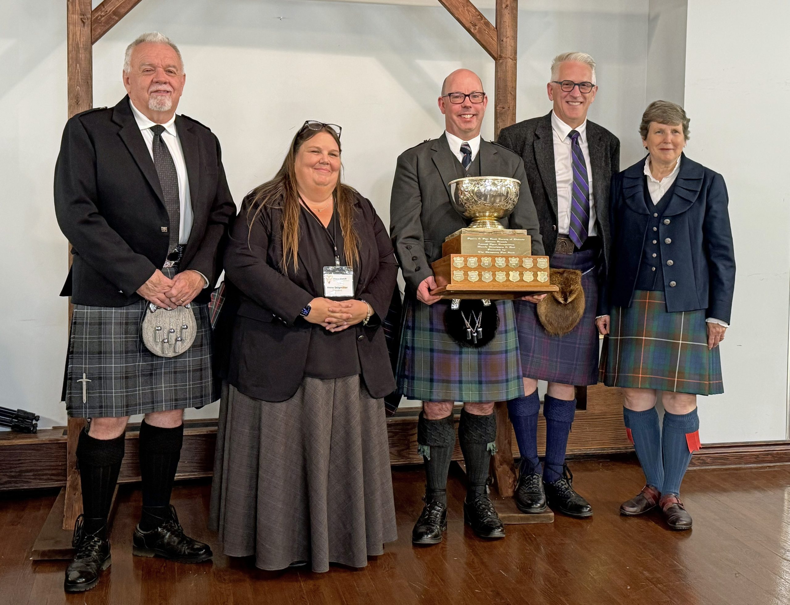 Andrew Hayes with the 2026 Glengarry Cup, and (L-R) adjudicator John Cairns, PPBSO Ottawa Branch President Anne Seigmiller, and judges Andrew Berthoff and Amy Garson