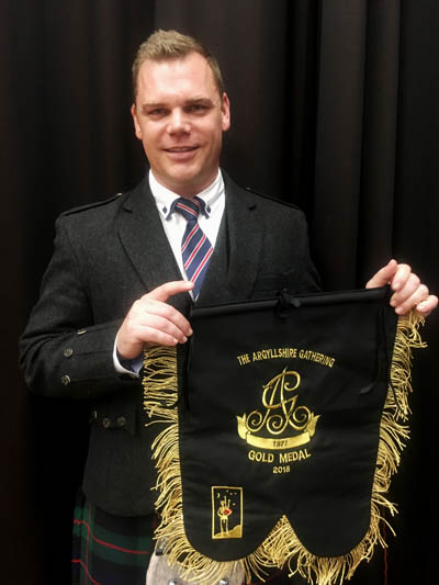 Oban Gold Medallist Stuart Easton with the bass drone banner that is awarded along with the actual Highland Society of London Gold Medal, which is presented at the Thursday games.