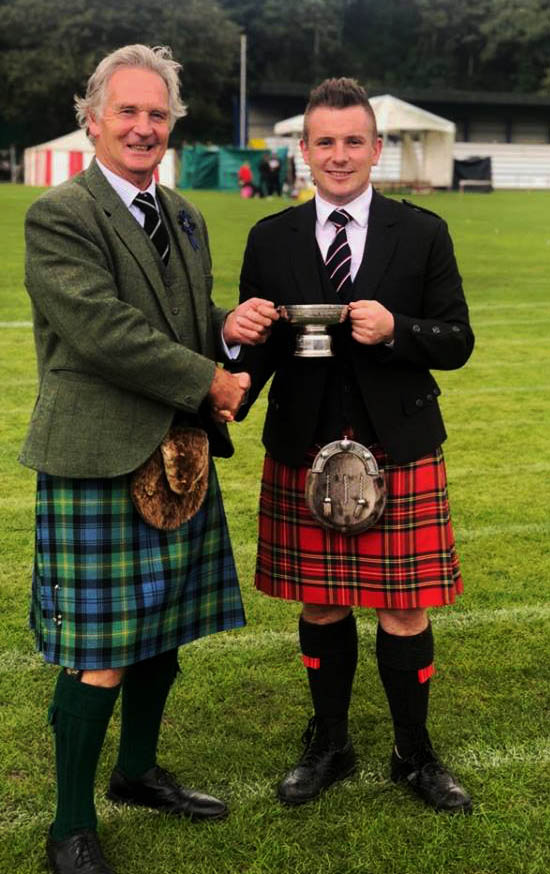Liam Kernaghan accepts the Angus Nichol Quaich for overall best B-Grade piper.