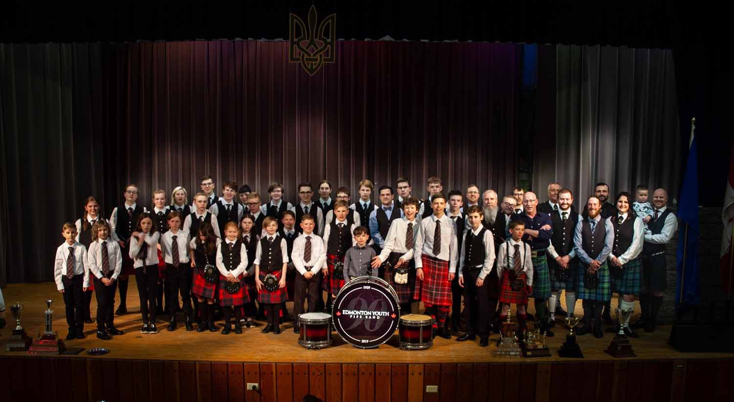 Edmonton Boys/Yough Pipe Band members, young and older, on stage at the organization's reunion concert.