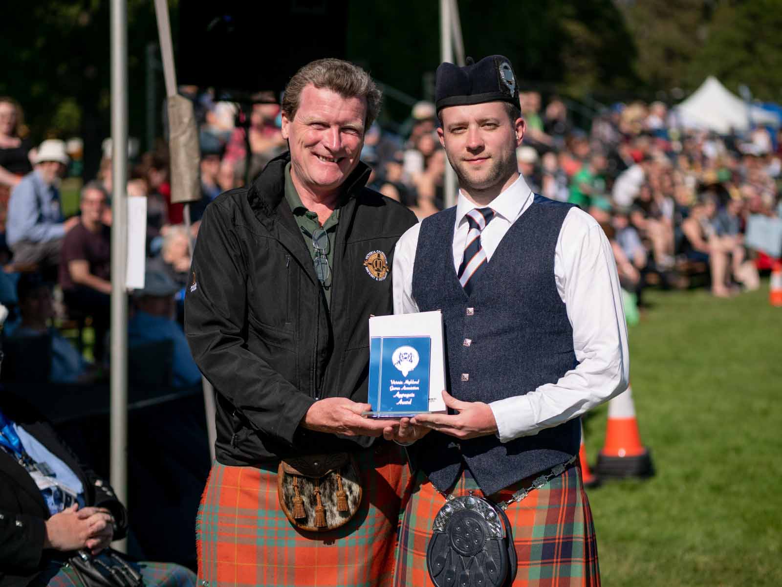 Alastair Lee accepts the 2019 Victoria Games Open Piobaireachd trophy from Victoria Caledonian Brewery & Distillery CEO Graeme Macaloney.